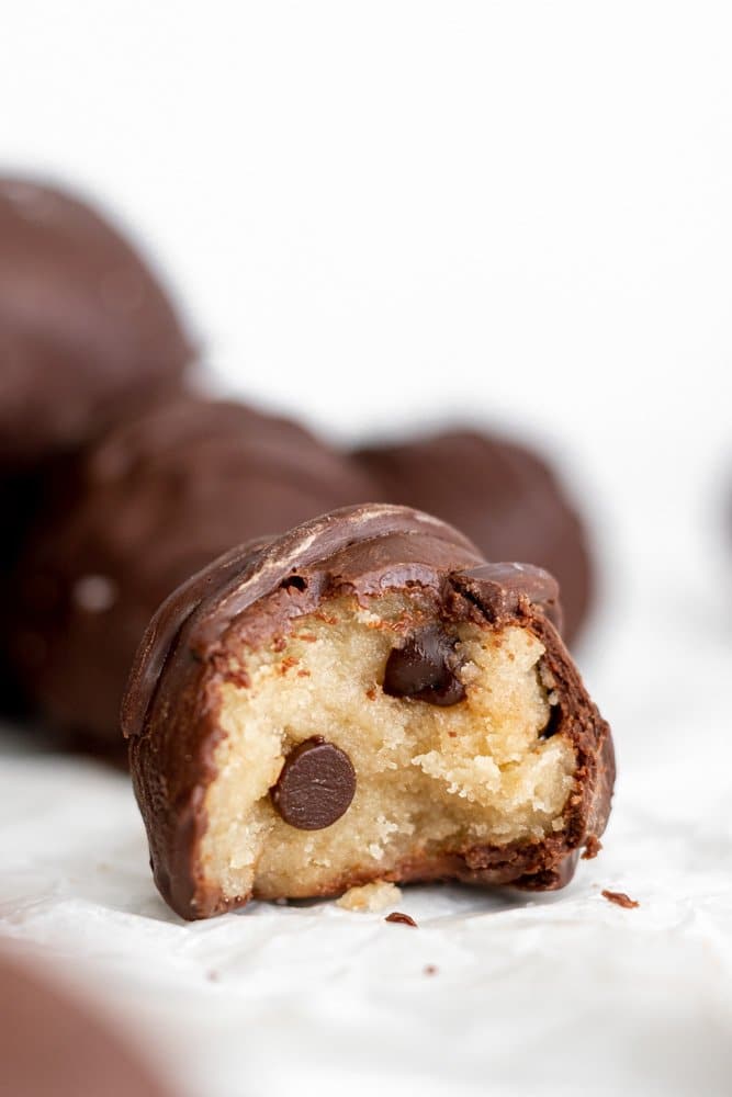 vegan cookie dough bite covered in chocolate with a bite out of it