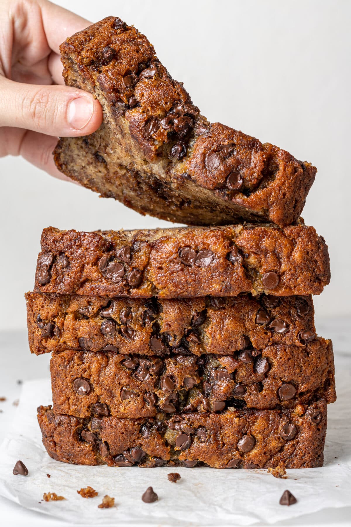 slices of dairy free banana bread stacked with a hand grabbing the top slice