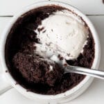 vegan mug cake with whipped cream on top and a spoon