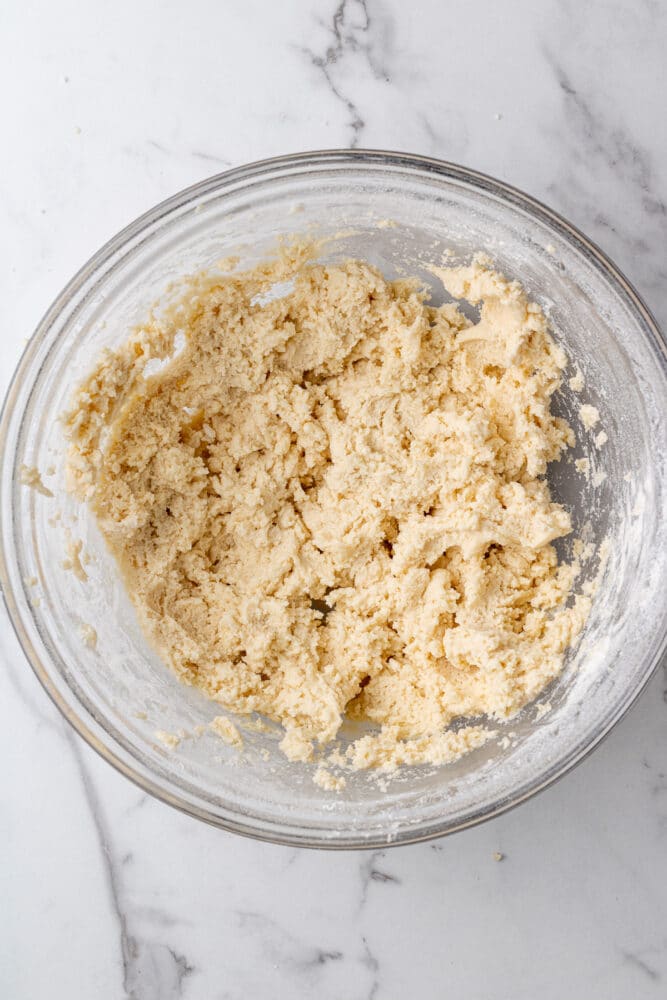 cookie dough in a glass bowl on a marble countertop.