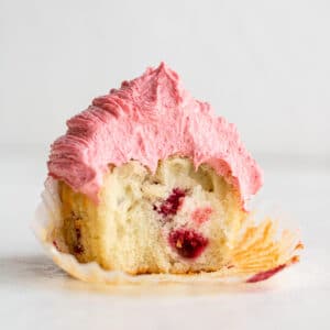 a raspberry cupcake with a bite taken out of it and raspberries inside