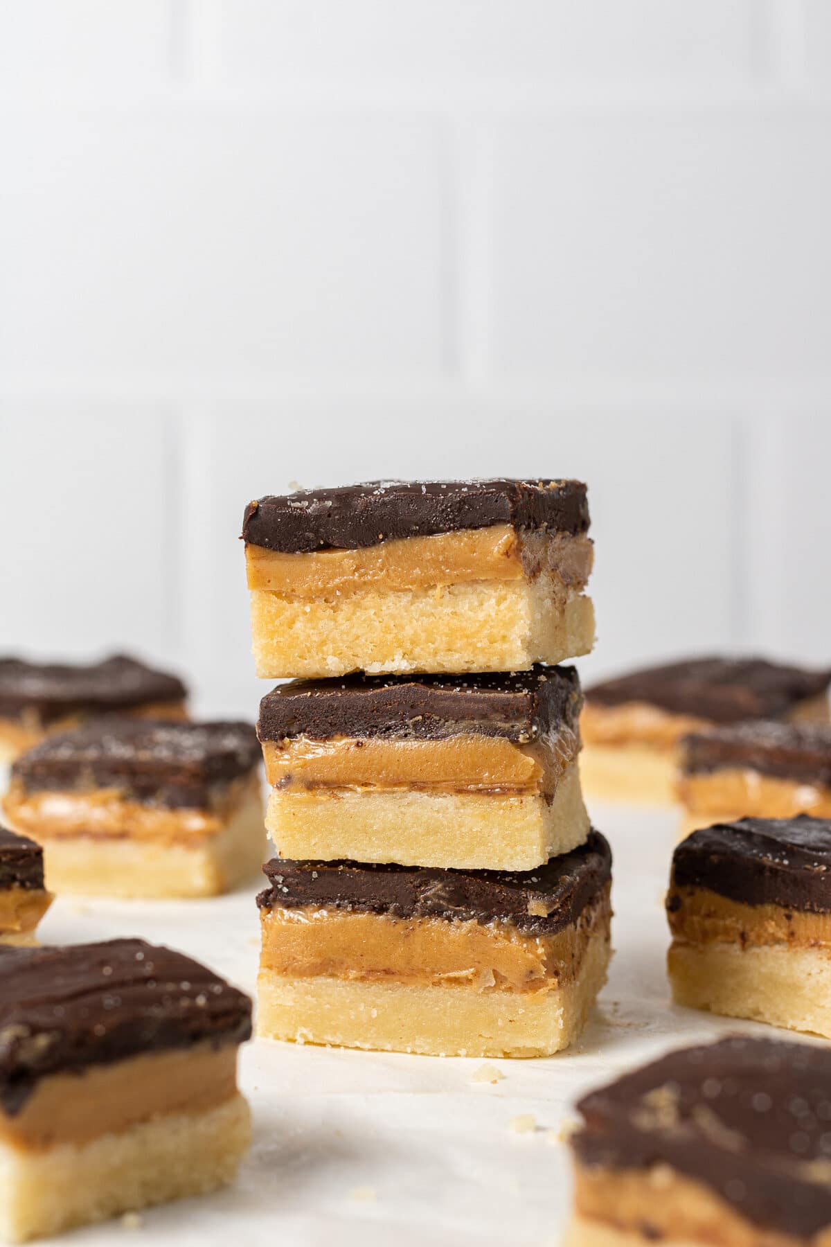 a stack of vegan millionaire shortbreads with more bars in the background