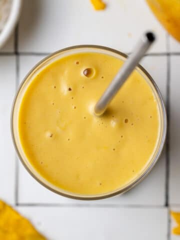 a mango shake in a glass with a straw