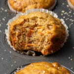 a banana carrot muffin on a muffin tray with more muffins around it