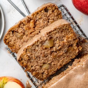 apple cake loaf sliced with cinnamon cream cheese icing and a sliced apple beside it