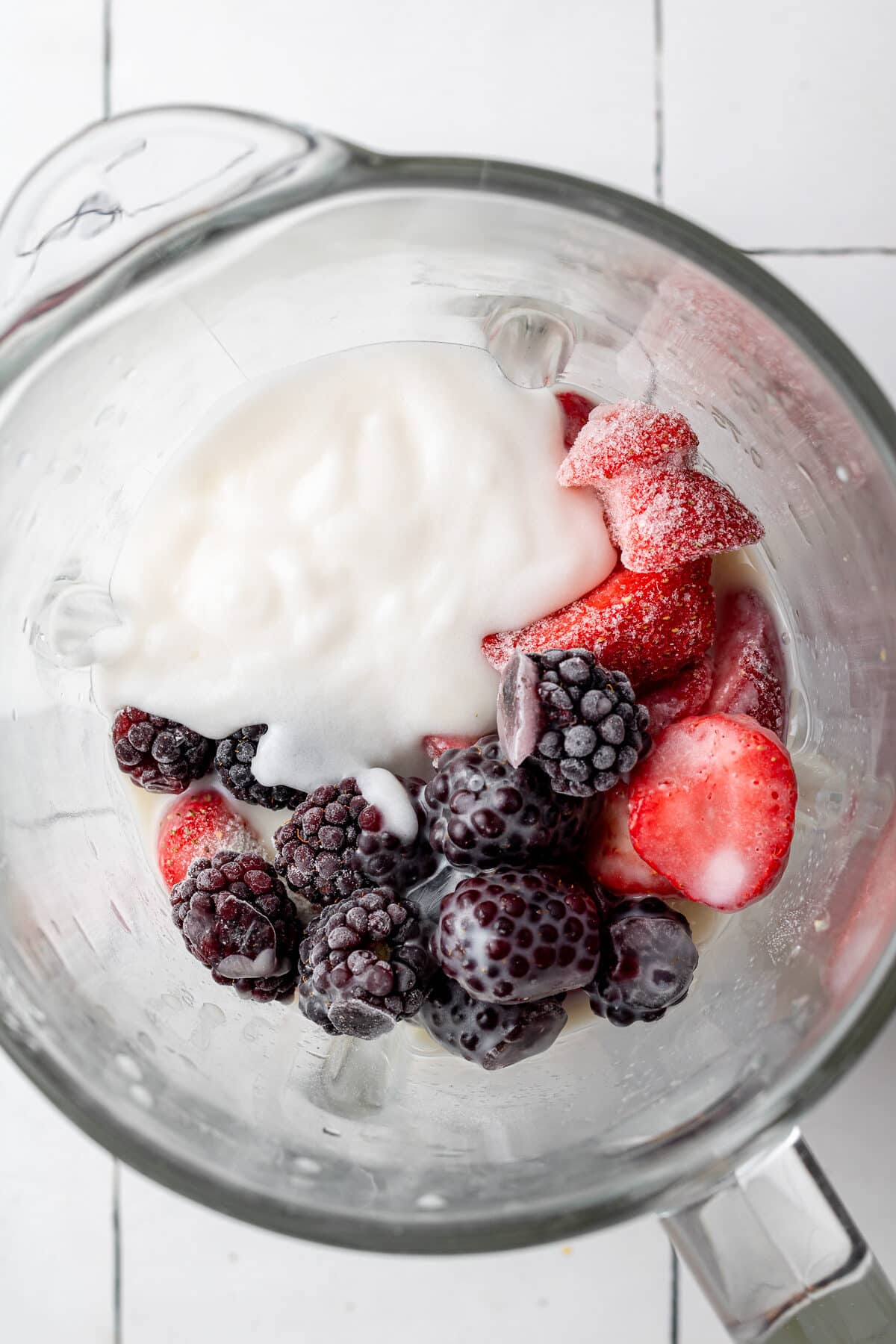 Yogurt, frozen strawberries, and frozen blackberries in a blender