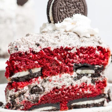 Piece of Red Velvet Oreo Cake topped with a whole Oreo on a plate