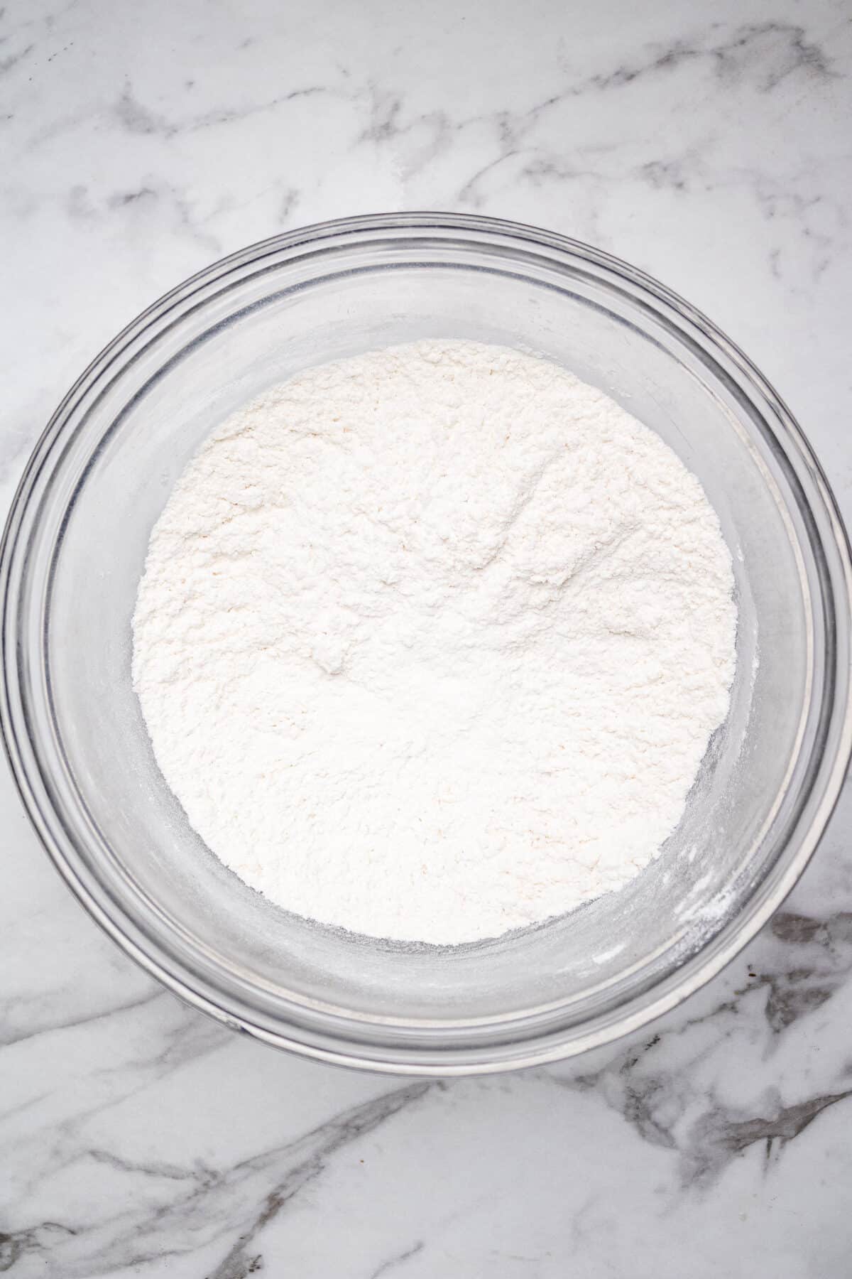 dry ingredients mixed together in a glass bowl on a marble countertop.