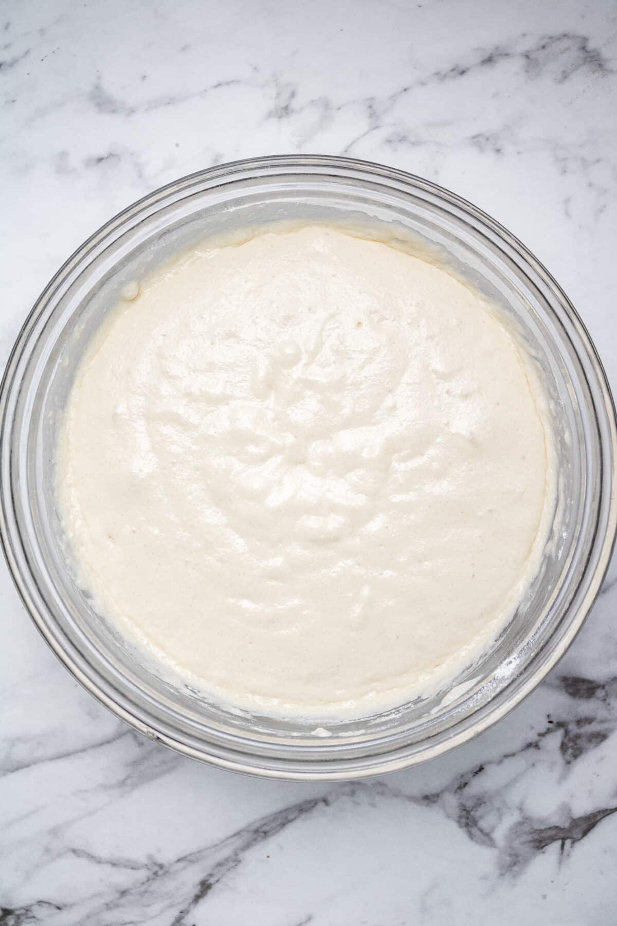 pancake batter in a glass bowl on a marble countertop.