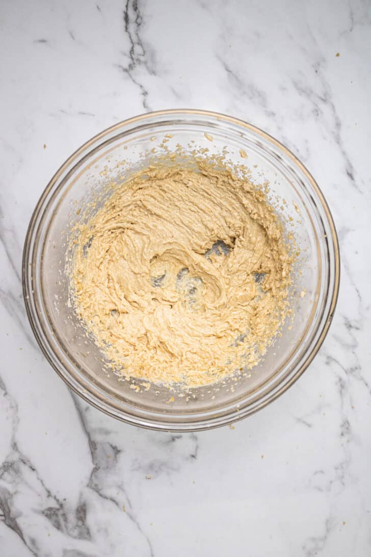 a mixing bowl with butter, sugars, vanilla, and egg yolk mixed together