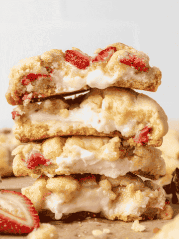 strawberry cheesecake cookies stacked on top of each other and split in half with cream cheese filling inside