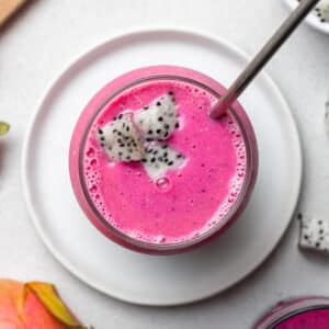 Dragon fruit strawberry smoothie pictured from above in a cup with a straw and topped with dragon fruit