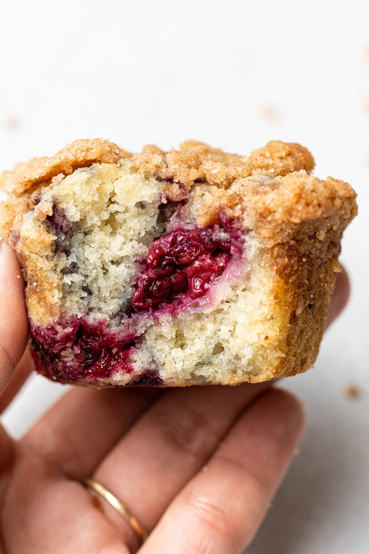 Hand holding a vegan blackberry muffin with a bite out of it 