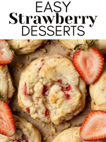 strawberry cookies on parchment paper with sliced strawberries around them
