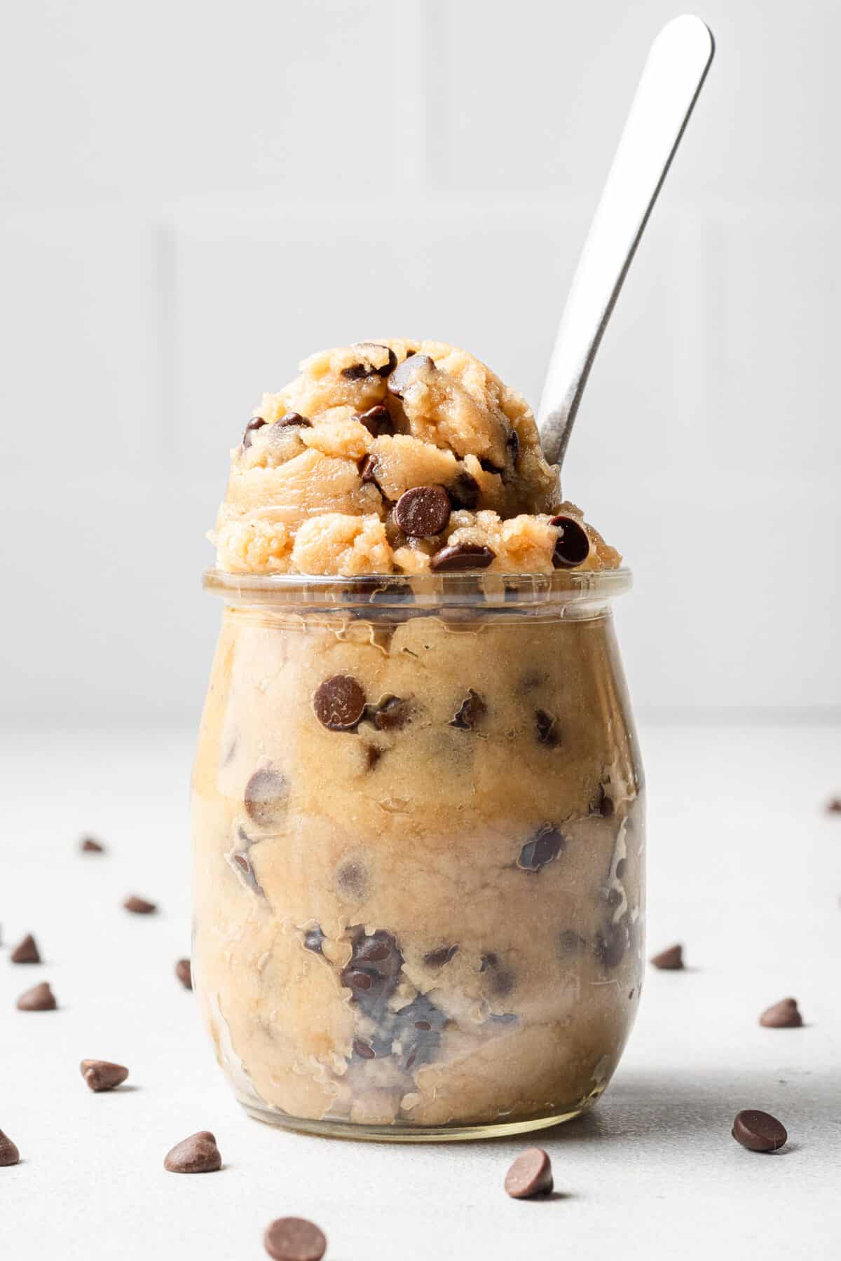 vegan edible cookie dough pictured in a glass jar with a spoon in it