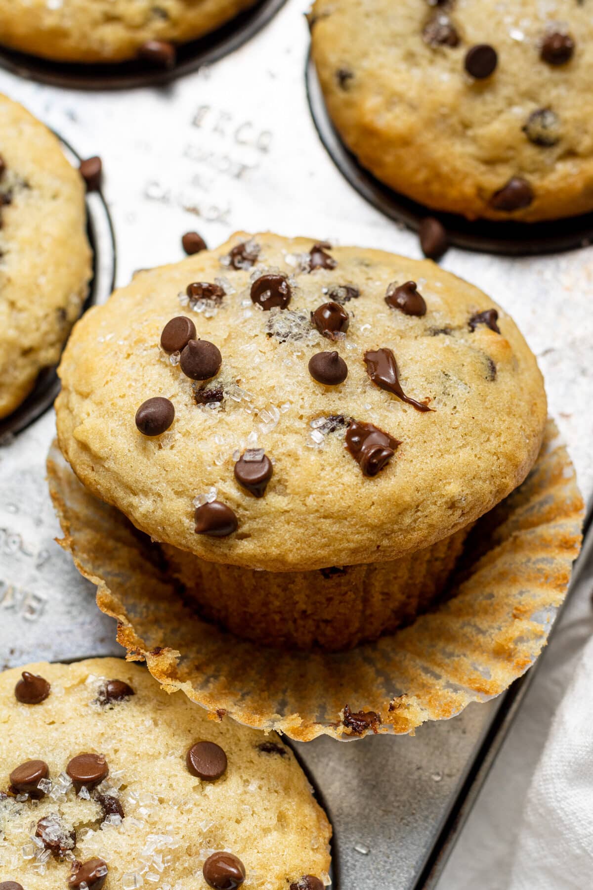 Vegan chocolate chip muffin with muffin wrapper peeled down and topped with chocolate chips