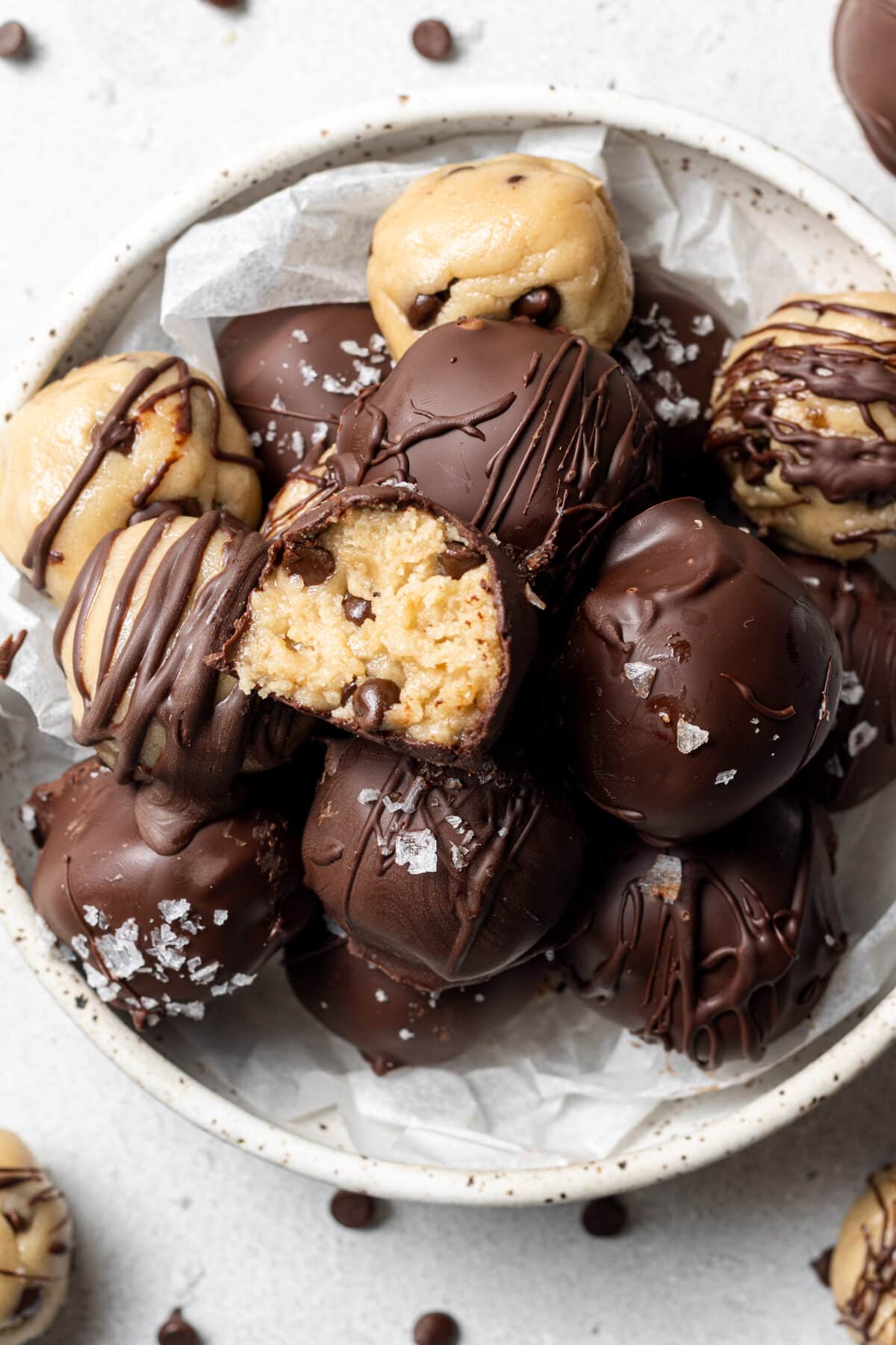 no bake cookie dough bites in a bowl with a bite out of one and chocolate chips scattered around them