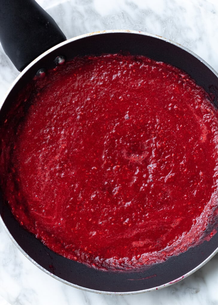 raspberry puree in a black frying pan.