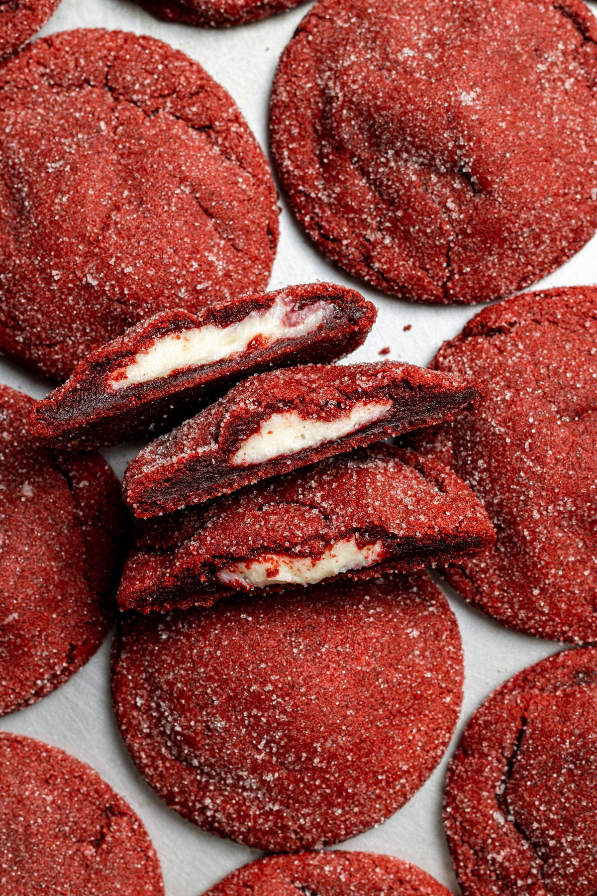 Large deep red in colour red velvet cheesecake cookies on a tray with a few broken in half