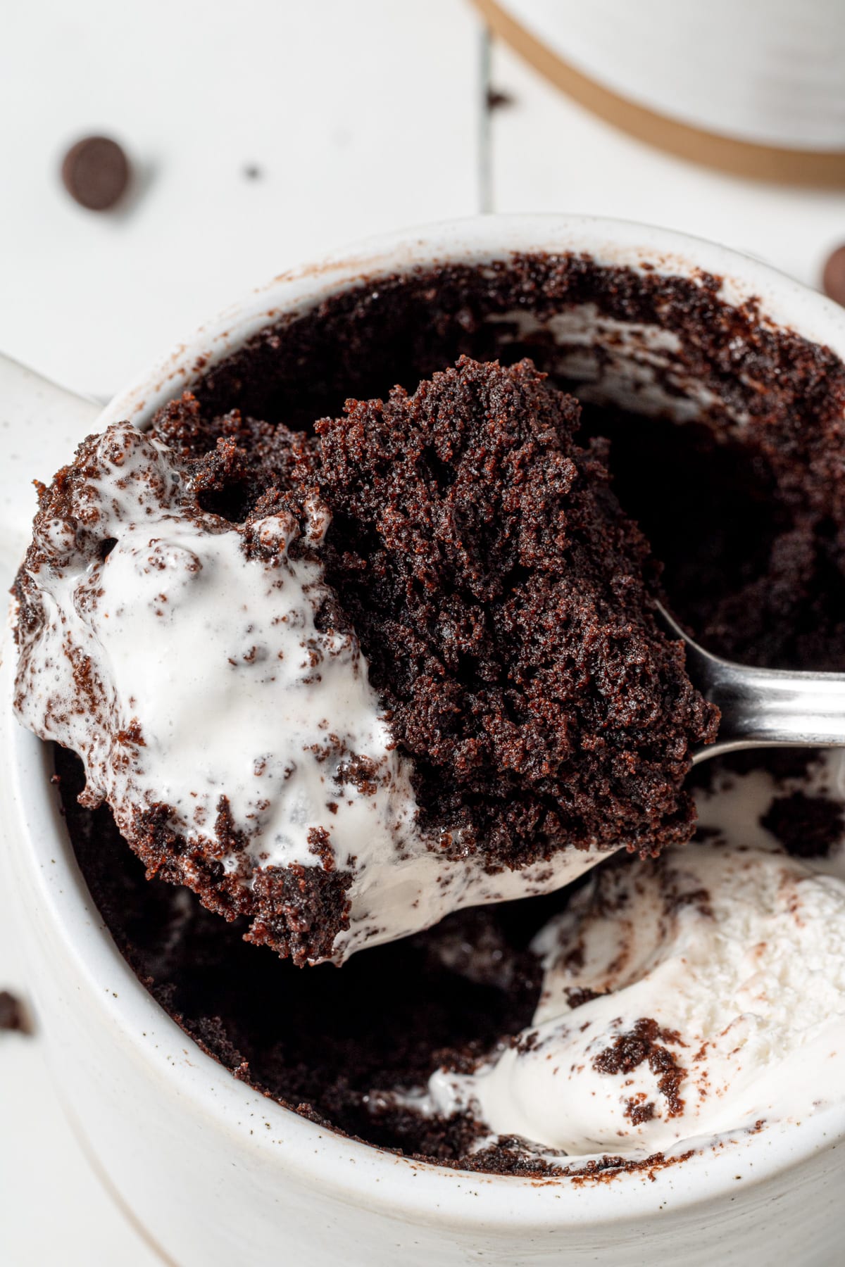 a scoop of vegan mug brownie with coconut whipped cream melting on top of it