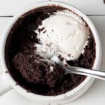 a vegan mug brownie with a scoop taken out of it and coconut whipped cream on top