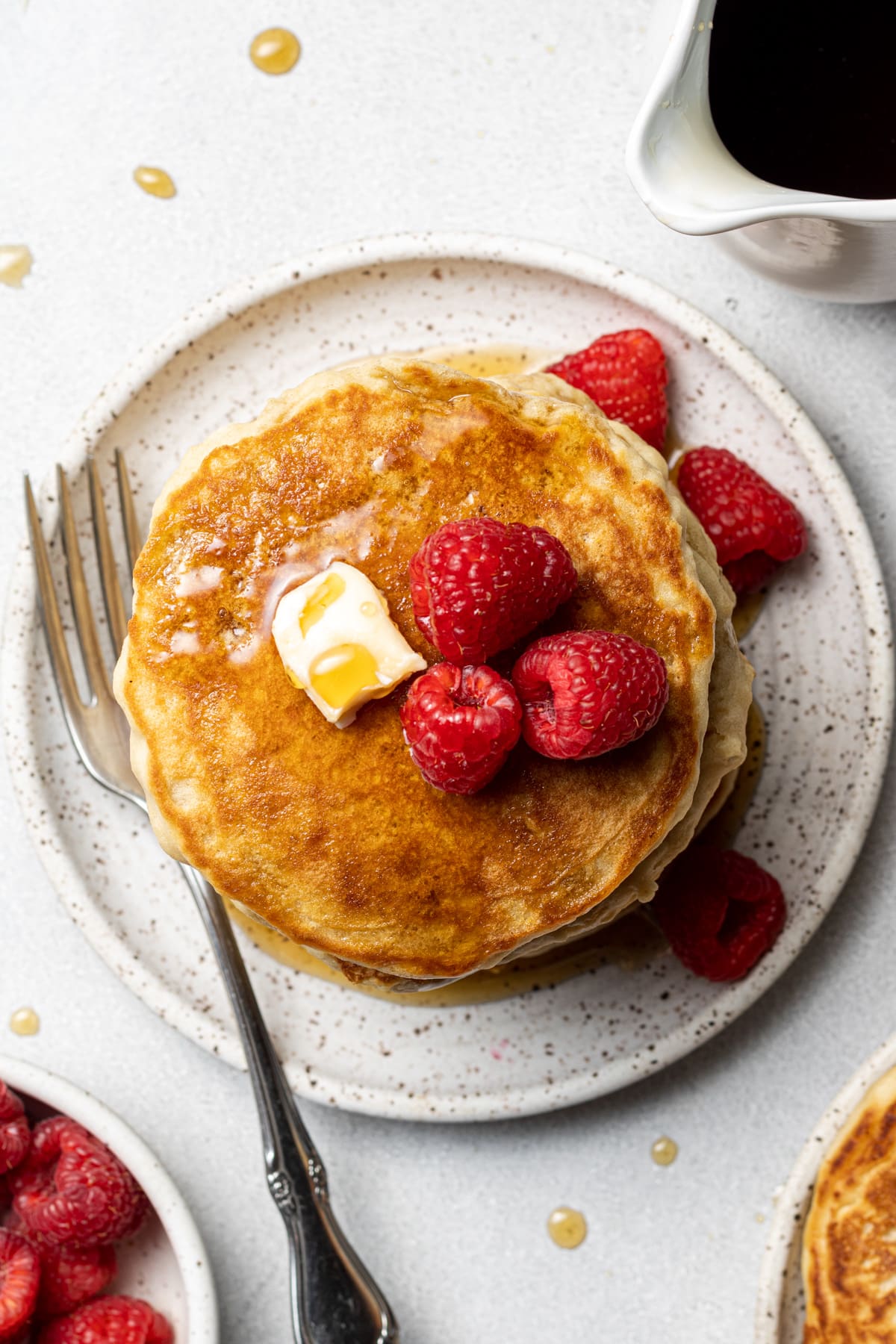 Almond milk pancakes topped with butter, syrup, and berries.