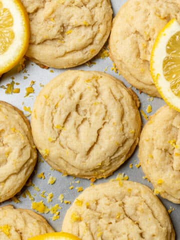 Soft lemon cookies on a baking tray with lemon slices