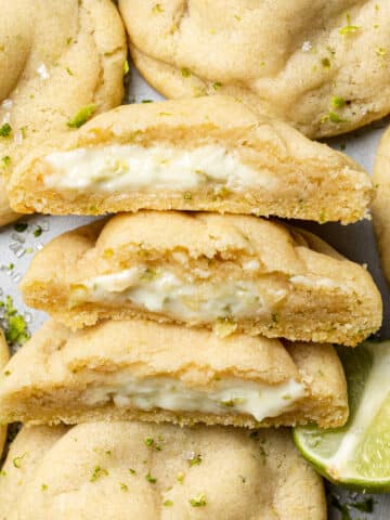 Key lime cookies on a tray with three halves cut open to reveal the stuffed inside
