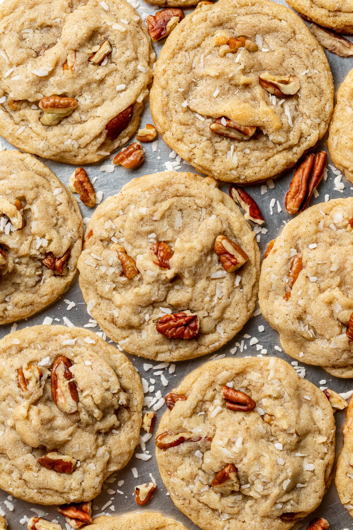 coconut pecan cookies on a tray with pecans and coconut flakes sprinkled around