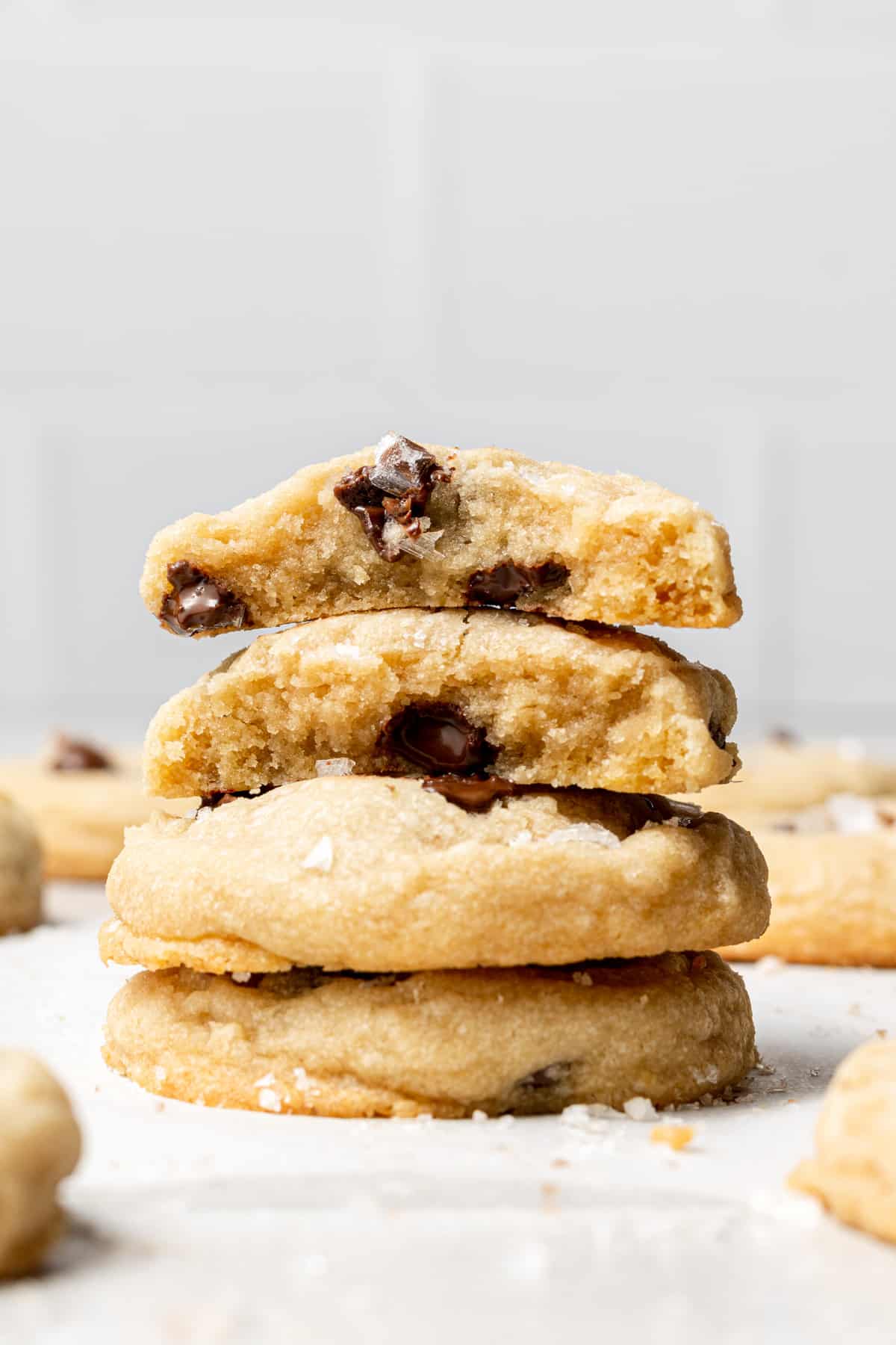 three Chocolate Chip Cookies Without Butter stacked on top of each other with the one on top split in half