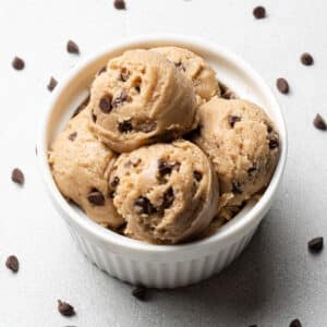 gluten free cookie dough scoops in a small bowl with chocolate chips scattered around