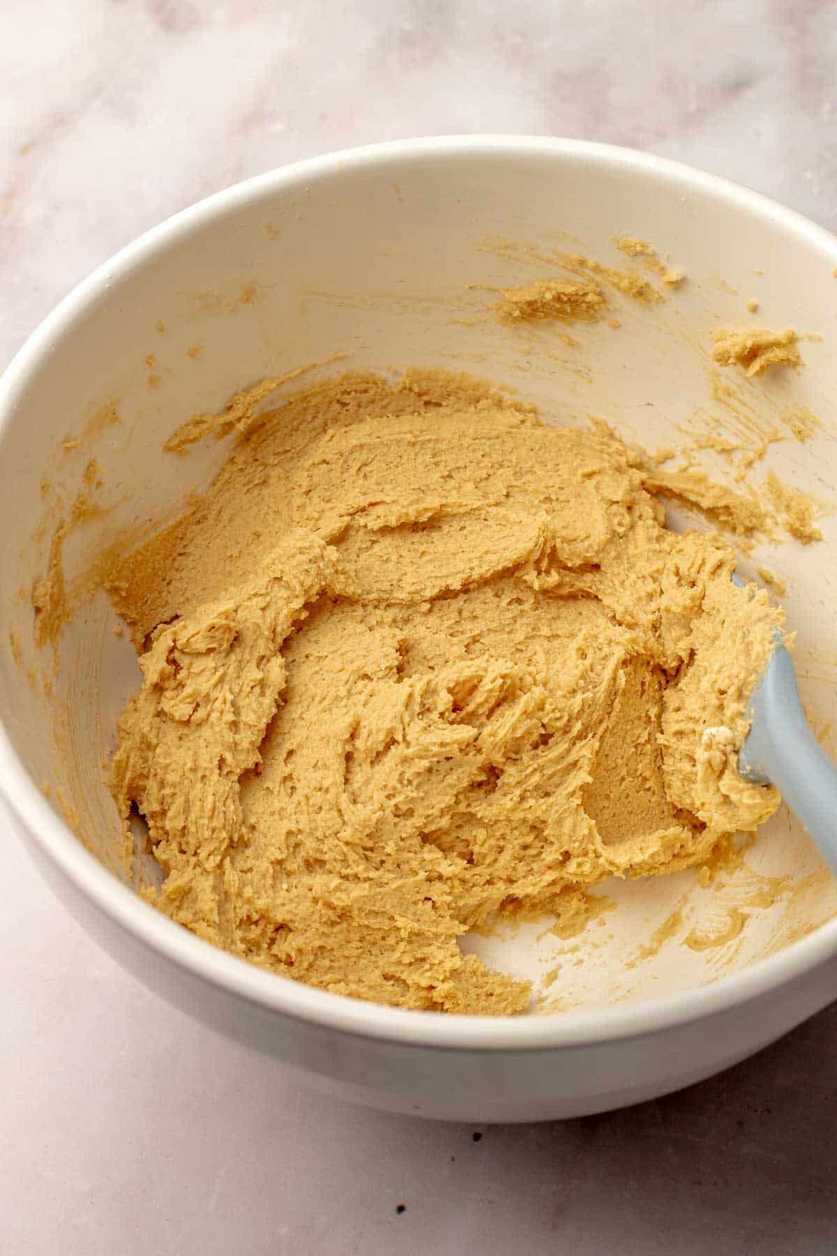 peanut butter cookie dough in a white bowl with a spatula in it.