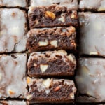 Close-up of glazed brownies cut into squares. The rich, chocolatey texture features visible nuts.