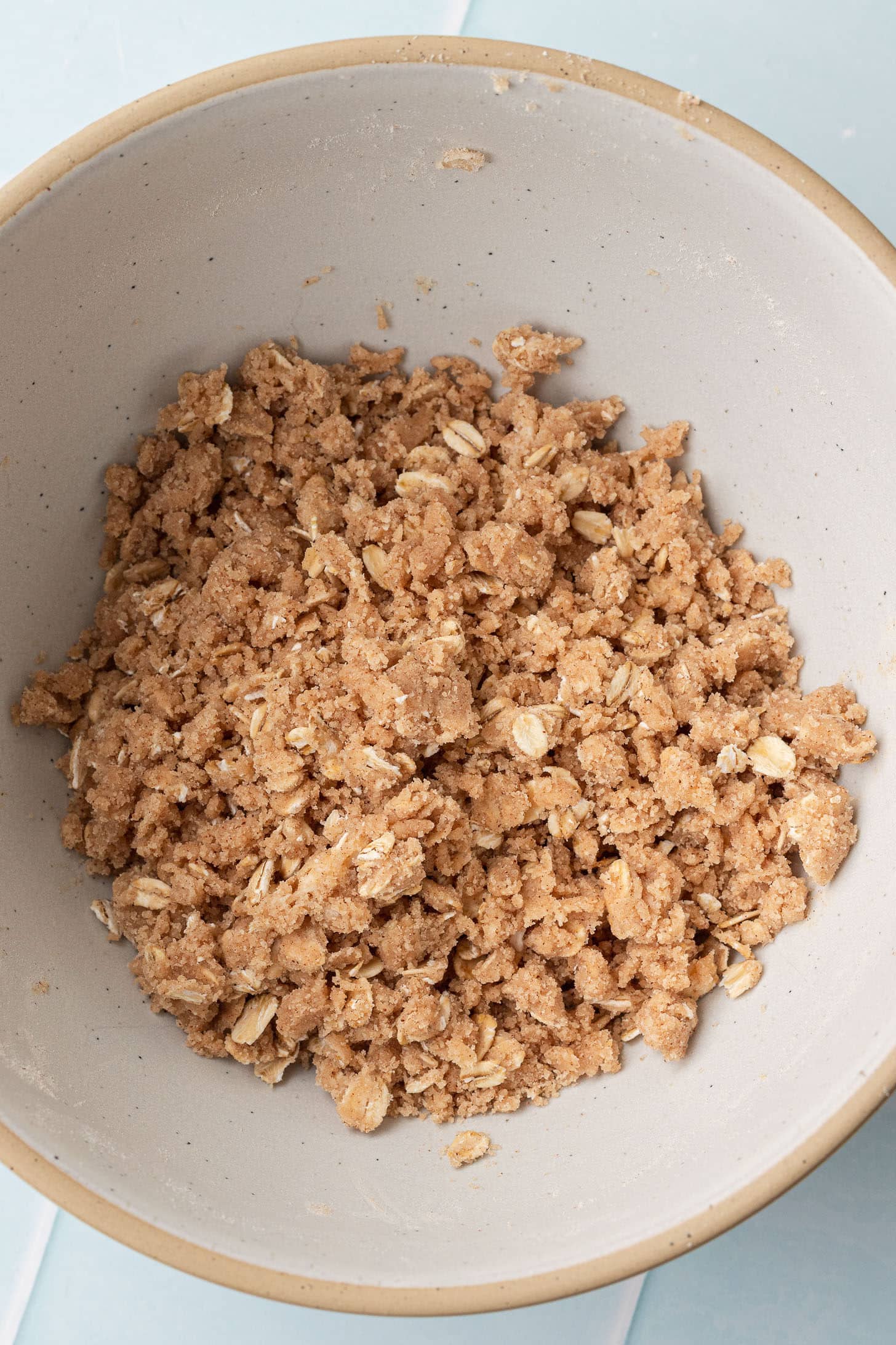 Cinnamon oat streusel topping with brown sugar and rolled oats mixed to a crumbly texture in a speckled ceramic bowl