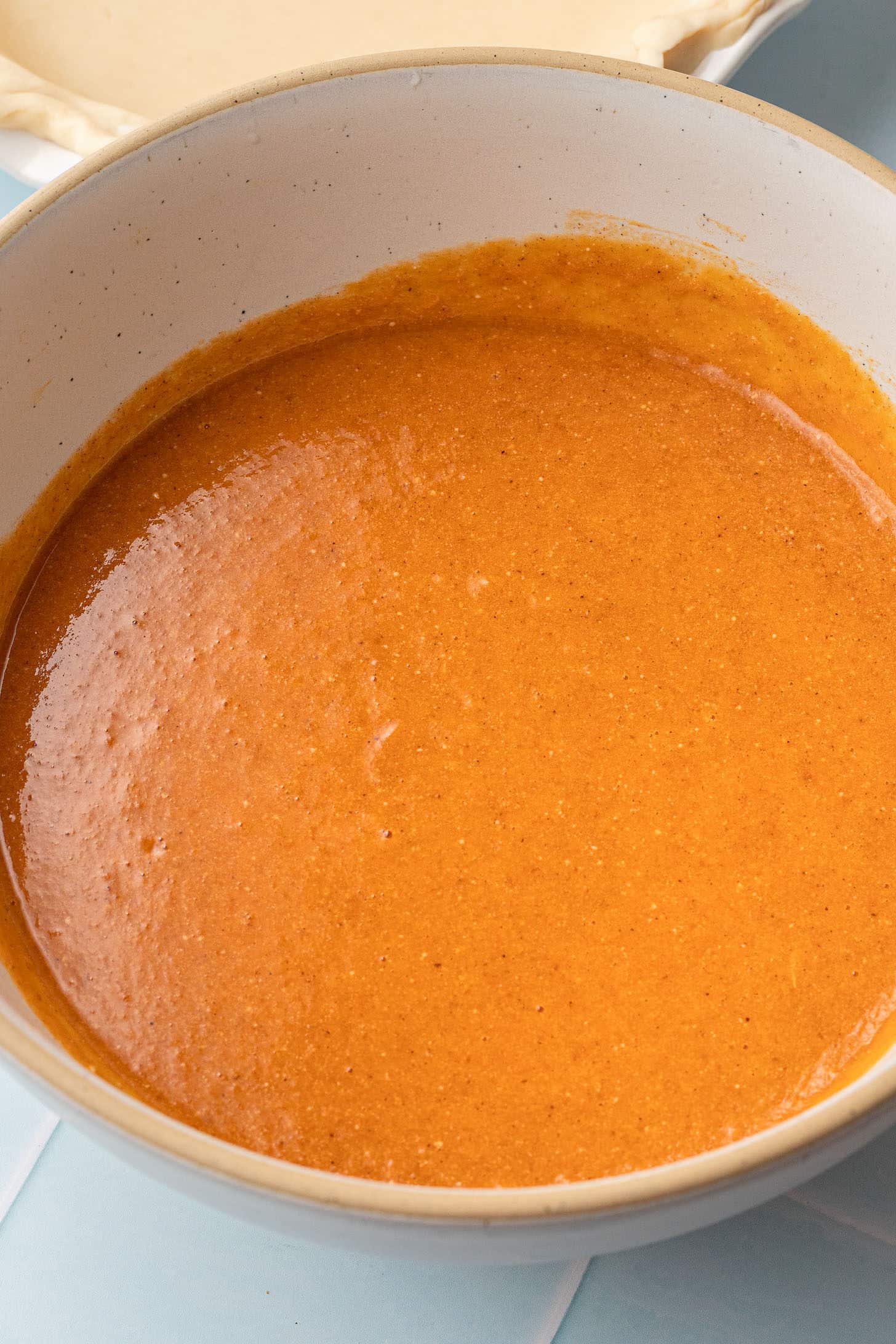Smooth, fully mixed pumpkin pie filling in a cream-colored mixing bowl, ready to be poured into the crust